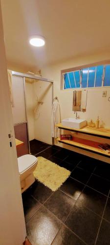 a bathroom with a white toilet and a sink at Chácara Sitara Lazer e Eventos - Casa Dourada in Caldas