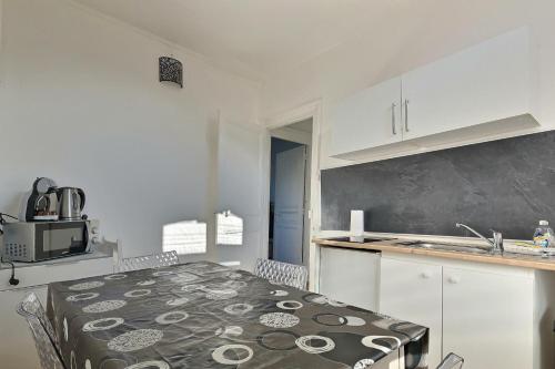 une cuisine avec des armoires blanches, une table et un évier dans l'établissement Le Duplex Amiens Centre, à Amiens