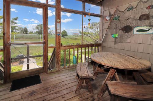 mesa de madera y banco en un porche con ventana en Misty's Thicket - Water access; Screened porches!, en Black Point Landing