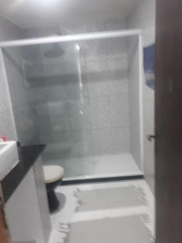 a white bathroom with a shower with a toilet at Pousada por do sol in Niterói
