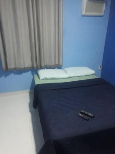 a blue room with a bed with two remote controls on it at Pousada por do sol in Niterói