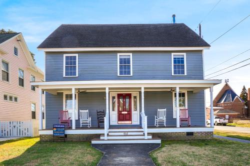 una casa azul con sillas rojas en el porche en Modest Junxtion - Lovingly Restored Home in Historic Cape Charles!, en Cape Charles