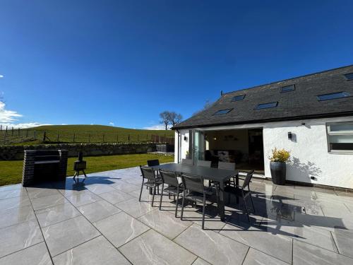 a patio with a table and chairs and a building at Beudy Pwll Pridd in Corwen