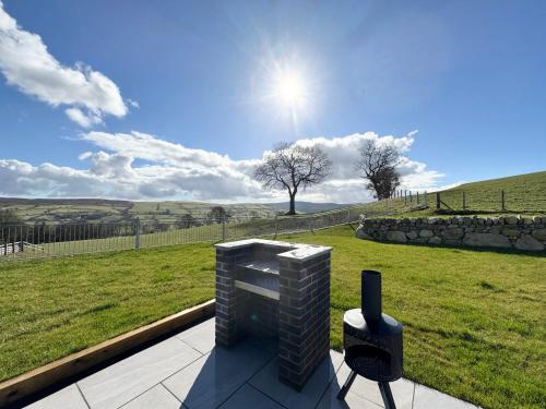 a fireplace on a patio with a view of a field at Beudy Pwll Pridd in Corwen