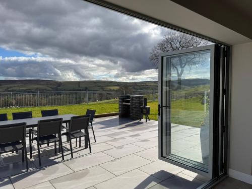a patio with glass doors and a table and chairs at Beudy Pwll Pridd in Corwen