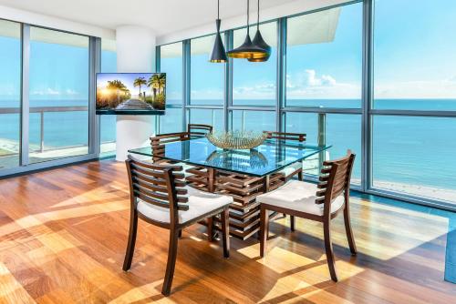 a dining room with a glass table and chairs at Oceanfront Private Condo at The Setai -2707 in Miami Beach