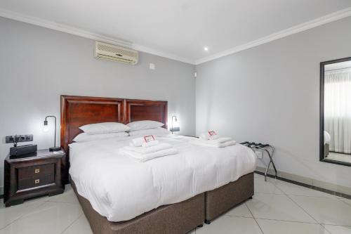a bedroom with a large bed with white sheets at Moyres Guest House in Witbank
