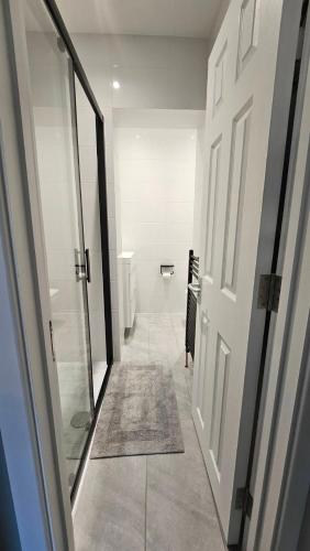 a hallway of a bathroom with a door and a rug at Place to Stay in Thames Ditton in London