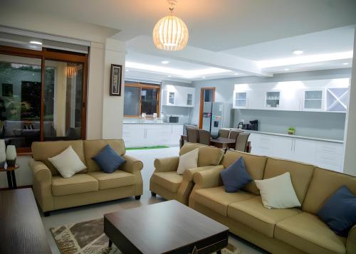 a living room with two couches and a kitchen at Brand New Condo Apartment in Kampala