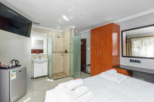 a bedroom with a white bed and a bathroom at Moyres Guest House in Witbank