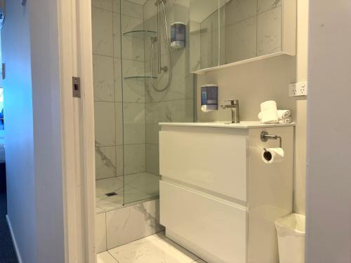 a white bathroom with a shower and a sink at Bluewater Hotel in Napier