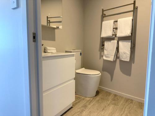 a bathroom with a toilet and a sink and towels at Bluewater Hotel in Napier