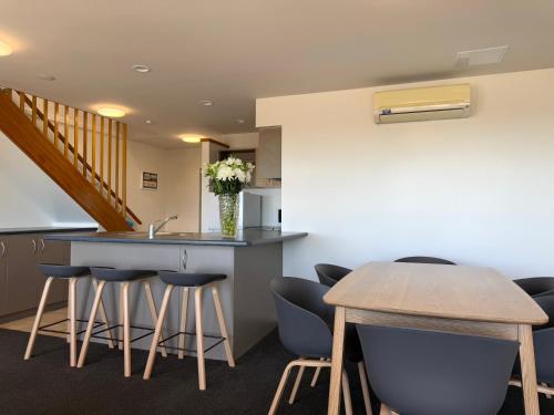 a kitchen with a bar with stools and a sink at Bluewater Hotel in Napier