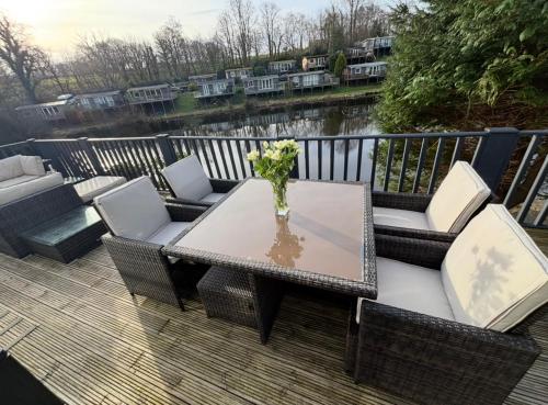 a patio with a table and chairs on a deck at Dillons Lakeside Lodge in Caeathro
