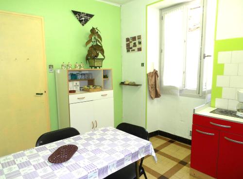 - une cuisine avec des murs verts, une table et un réfrigérateur dans l'établissement L'Andronne, à Vallon-Pont-dʼArc