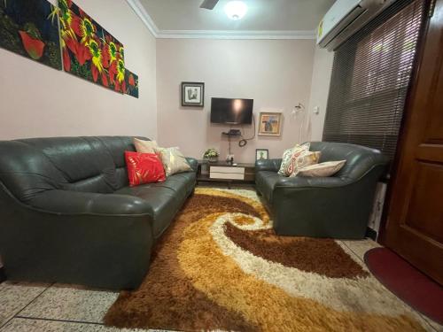 a living room with two leather couches and a rug at The Loft in Teshi