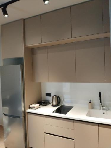 a kitchen with white cabinets and a stainless steel refrigerator at Simple, Calm and Luxurious in Kalamata