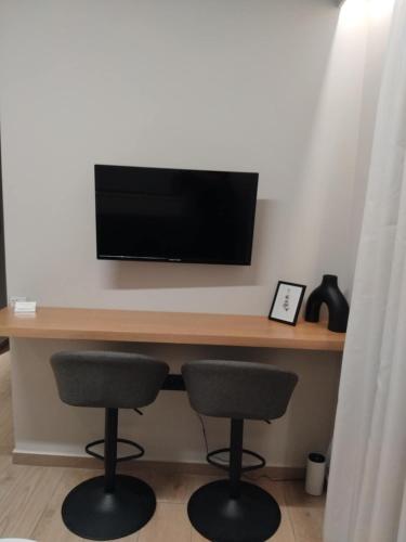 a desk with two chairs and a television on a wall at Simple, Calm and Luxurious in Kalamata