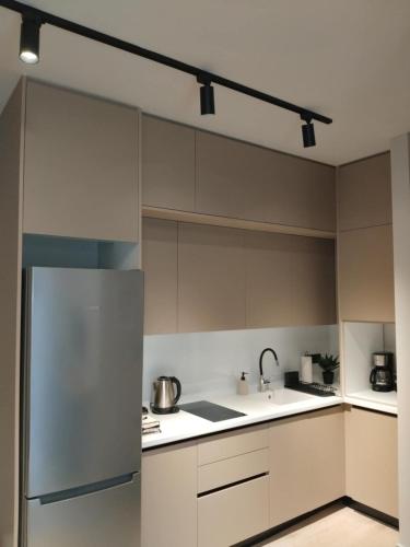 a kitchen with white cabinets and a stainless steel refrigerator at Simple, Calm and Luxurious in Kalamata