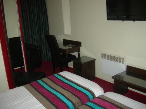 a hotel room with a bed and a desk at Hôtel du Val de Seine in Mantes-la-Jolie