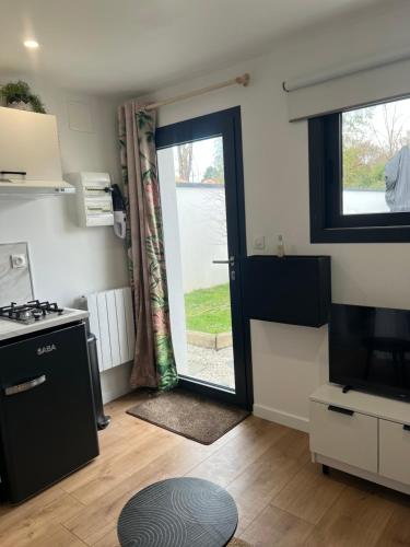 une cuisine avec une porte menant à une terrasse dans l'établissement Chambre indépendante - Les halbrans, à Saint-Aignan-Grand-Lieu