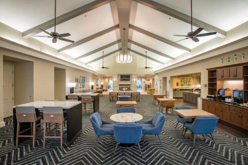 a lobby with tables and chairs and a kitchen at Pensacola Suites Hotel in Pensacola