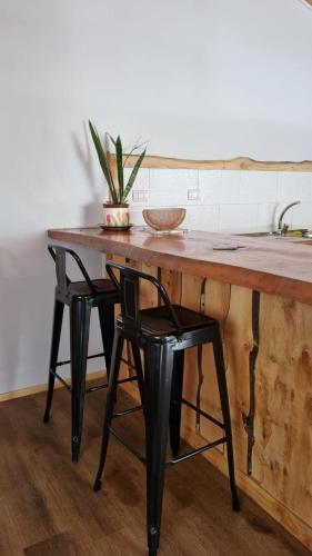 a wooden table with two black chairs and a sink at Cabaña familiar en el campo a 15 minutos del centro de Melipeuco in Rumiñano