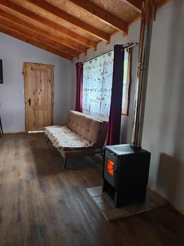 a living room with a couch and a stove at Cabaña familiar en el campo a 15 minutos del centro de Melipeuco in Rumiñano