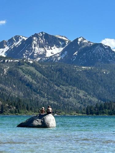two people sitting on a rock in the water at Whispering Pines in June Lake