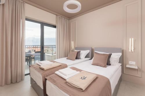two beds in a hotel room with a balcony at Saint Matthew Place in Dobrota