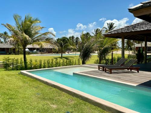 ein Pool mit einer Bank neben einem Haus in der Unterkunft Casa do vento - Ilha do Guajiru in Itarema