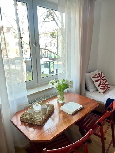 a table with a vase of flowers and a window at Agapella Apartamemty- Villa Agapella 250m from the beach in Sopot