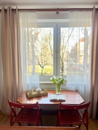 a table with a vase of flowers and a window at Agapella Apartamemty- Villa Agapella 250m from the beach in Sopot