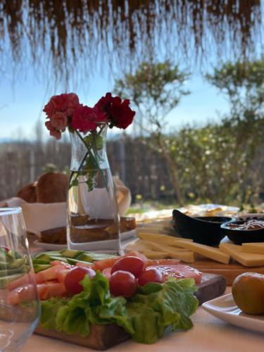 a table with flowers in a vase and food on it at Natyra e Ishullit -Resort- in Ishull-Shëngjin