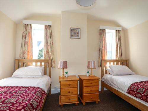 two beds in a room with two windows at Glan Y Don in Abersoch