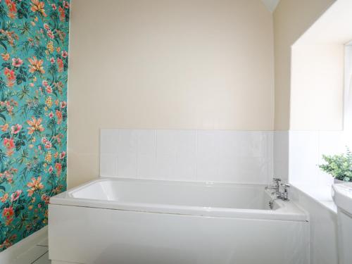 a white bath tub in a bathroom with a floral wallpaper at Glan Y Don in Abersoch