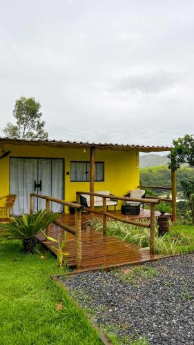 a yellow house with a wooden deck in front of it at Cabanadepaty in Paty do Alferes