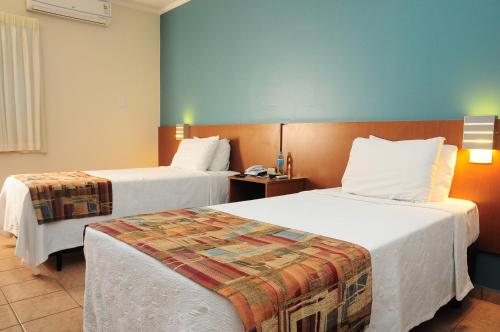 a hotel room with two beds and a telephone at Hotel Riviera in Araçatuba