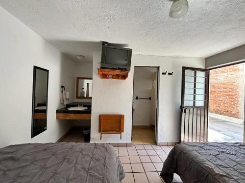 a bedroom with a bed and a television on a wall at Hotel bugambilias in Valle de Bravo