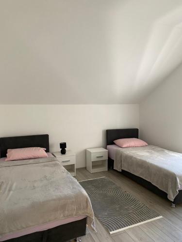 two beds in a room with white walls and pink pillows at Apartment Loft 22 in Mostar
