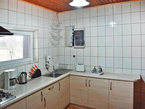 a white tiled kitchen with a sink and a window at holiday home with thatched roof, Rekowo in Rekowo