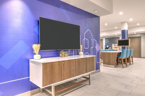 a large flat screen tv on a wall in a lobby at Holiday Inn Express & Suites Austin Airport East by IHG in Austin