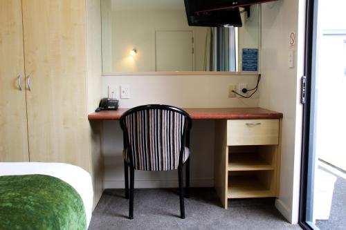 a room with a desk with a chair and a mirror at Bella Vista Motel Mosgiel in Mosgiel