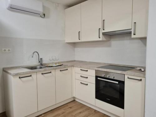 a white kitchen with white cabinets and a sink at House Dalmatika Zaton in Zaton