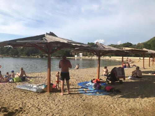 Ein Mann, der unter einem Schirm am Strand steht. in der Unterkunft House Dalmatika Zaton in Zaton