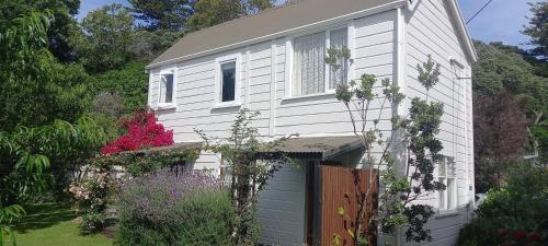 a white house with a garage in a garden at Kowhai Cottage Whanganui in Whanganui