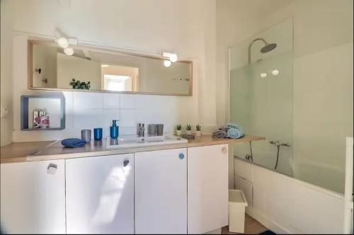 une salle de bain blanche avec un lavabo et un miroir dans l'établissement Nyméria, à Nîmes