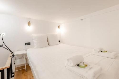 une chambre avec un lit blanc avec des serviettes dessus dans l'établissement Cosy Duplex in Central Paris, à Paris