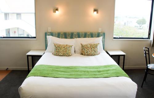 a bedroom with a large white bed with two windows at Bella Vista Motel Mosgiel in Mosgiel