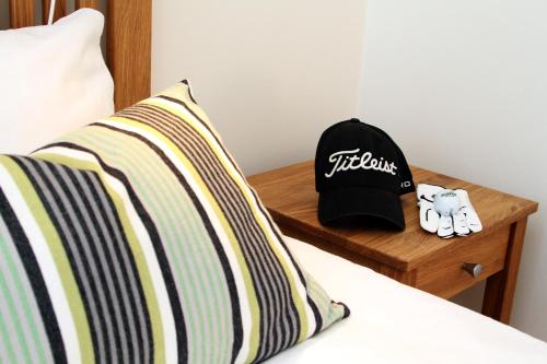 a bed with a hat on a wooden night stand at Sand Golf Club in Bankeryd